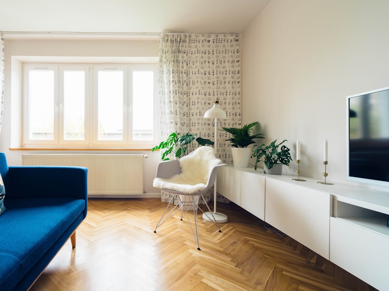 Séjour meublé avec canapé, parquet et grande fenêtre